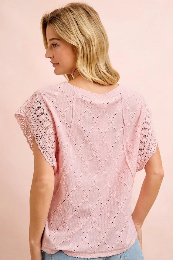 Summer knit top displayed at a three-quarter angle to show the airy crochet sleeves and feminine silhouette.