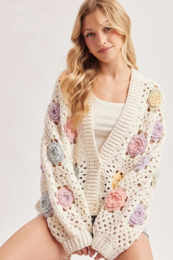 Ivory open stitch crochet cardigan with 3D pastel floral appliqués, voluminous balloon sleeves, and front buttons for a Cottagecore style.