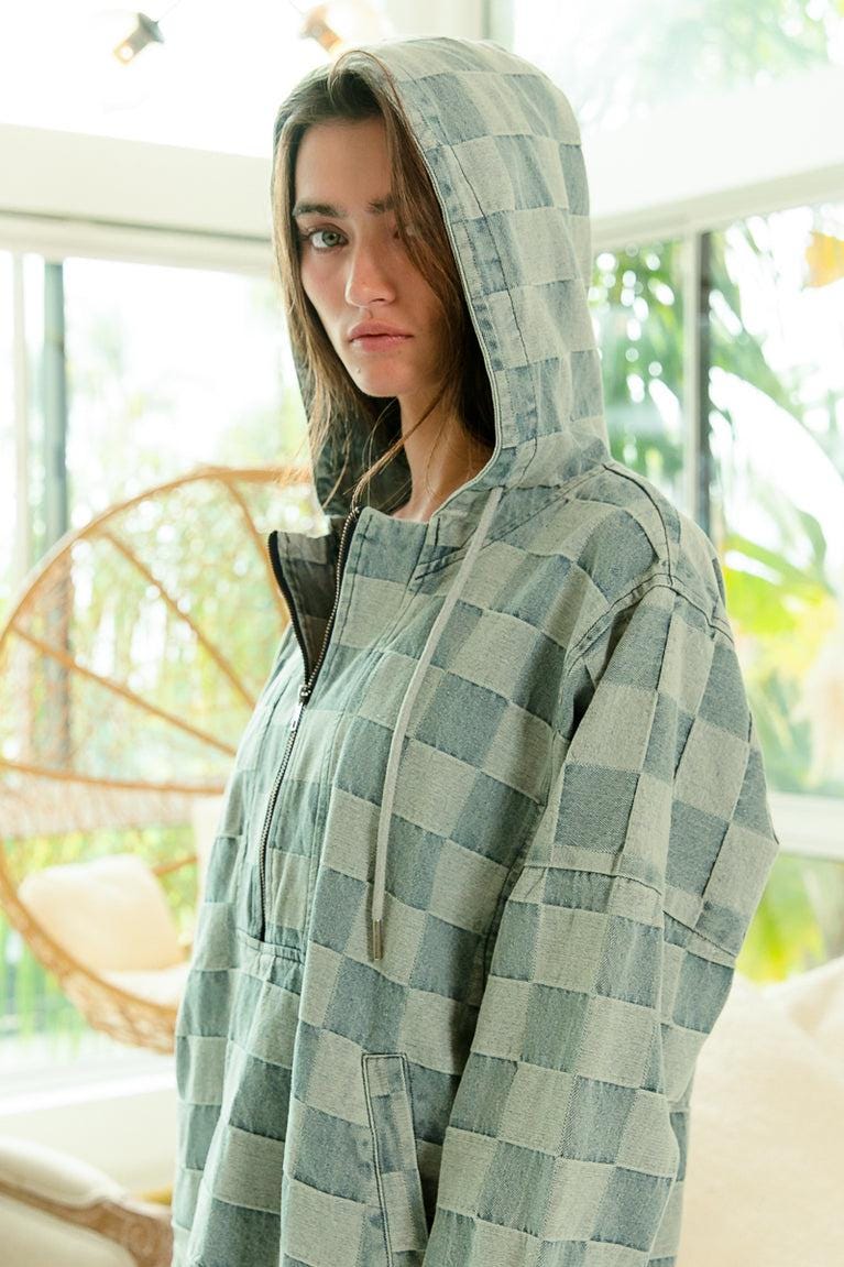 Detail view of the silver half-zip hardware on a muted blue and gray checkerboard core hoodie.