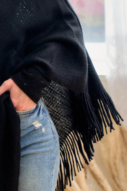 Detail of the asymmetrical hemline and playful fringe on a boho-chic black shawl for festival fashion
