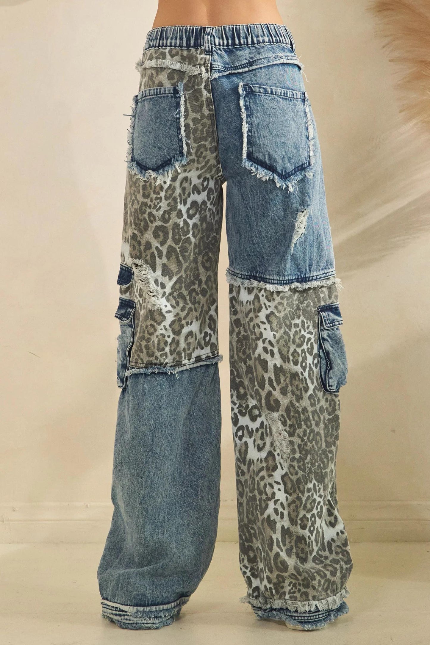 Full body shot of blue distressed cargo pants in a cotton blend with leopard print styling