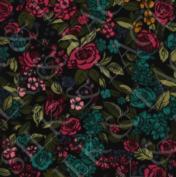 Folded dark floral pajama pants showcasing the magenta and teal botanical design on soft plush fleece