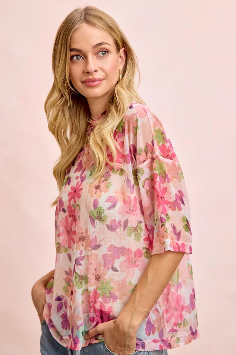 Detailed view of the crew neckline on this botanical print mesh top in vibrant pink and green hues