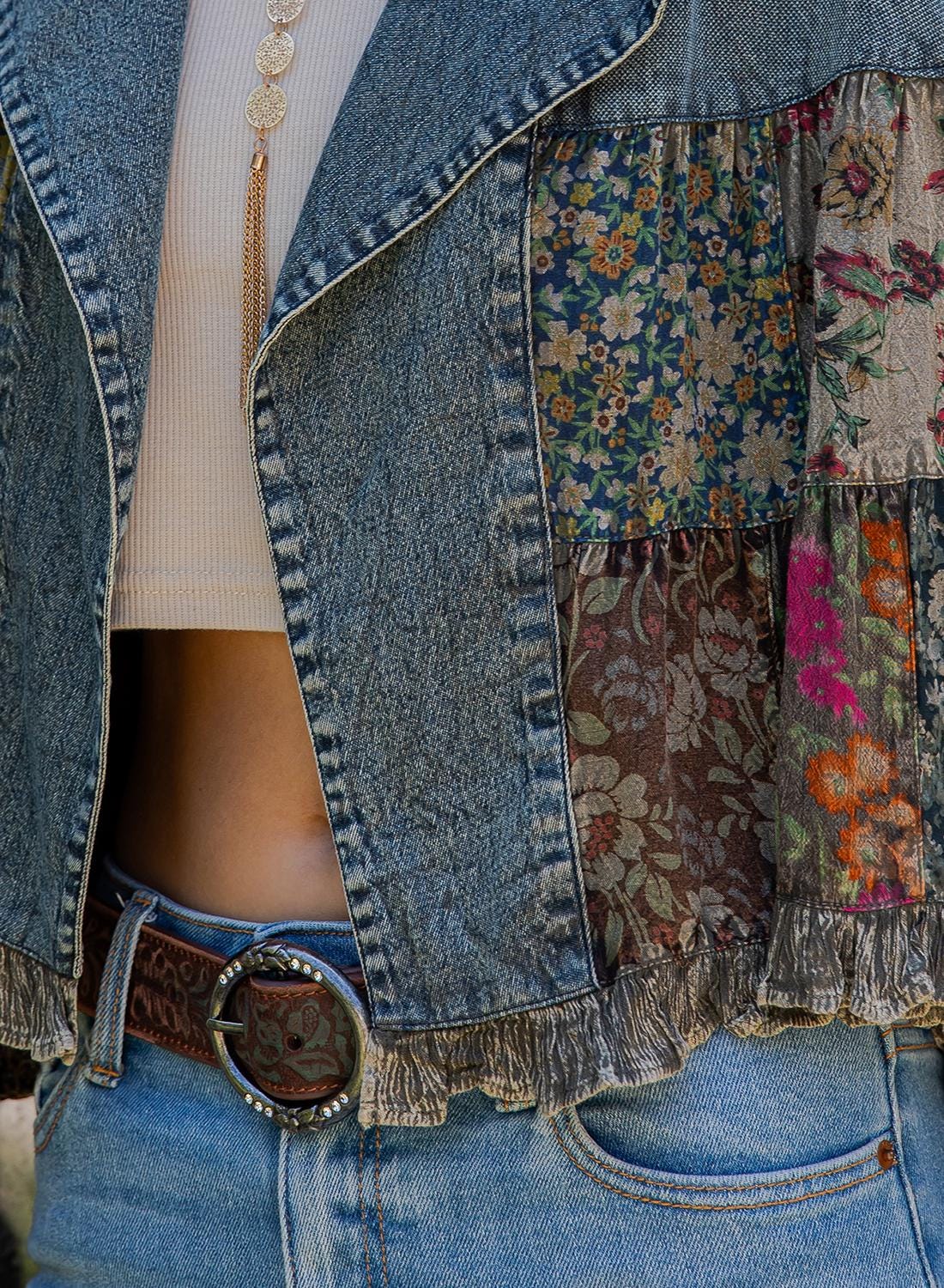 Side angle of a retro bohemian cropped denim coat featuring earth tone multicolor floral embroidery