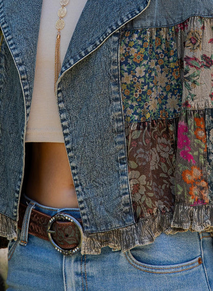 Side angle of a retro bohemian cropped denim coat featuring earth tone multicolor floral embroidery