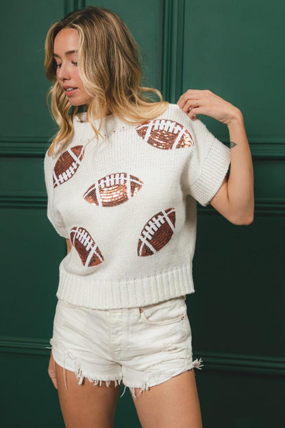 Close-up of shimmering bronze sequin footballs on the white knit game day top