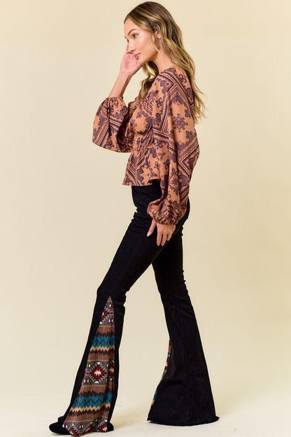 Front view of high waisted black flare jeans with colorful Aztec print inserts at the hem
