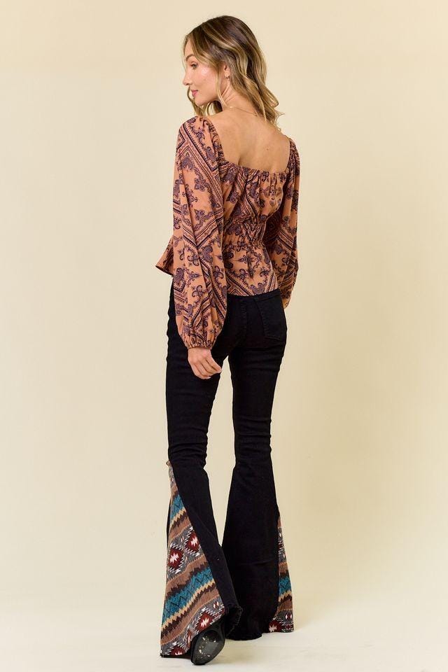 Close-up of geometric Aztec print fabric inserts in teal and red on black denim flare jeans