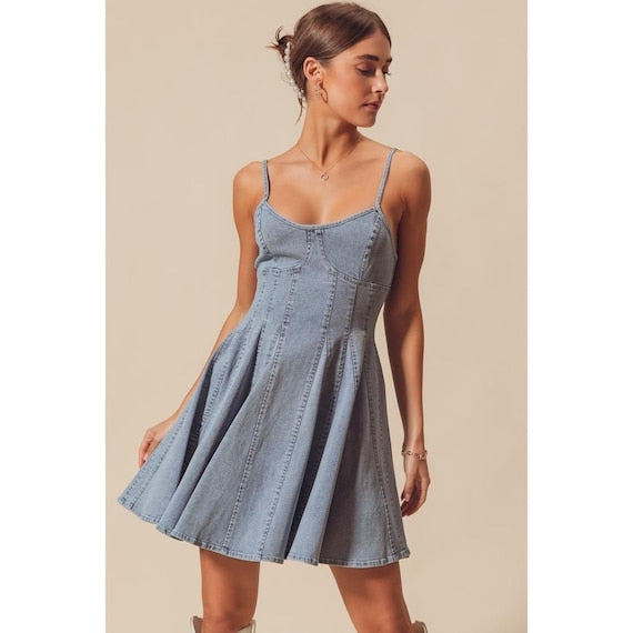 A model twirling in the flared paneled mini dress to demonstrate the movement of the light wash fabric