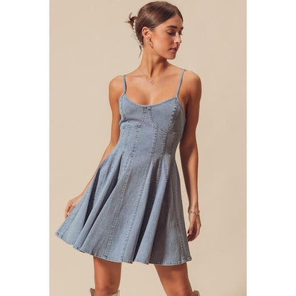 A model twirling in the flared paneled mini dress to demonstrate the movement of the light wash fabric