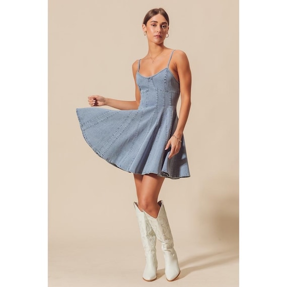 Model wearing the coastal cowgirl style denim mini dress paired with boots for a western aesthetic