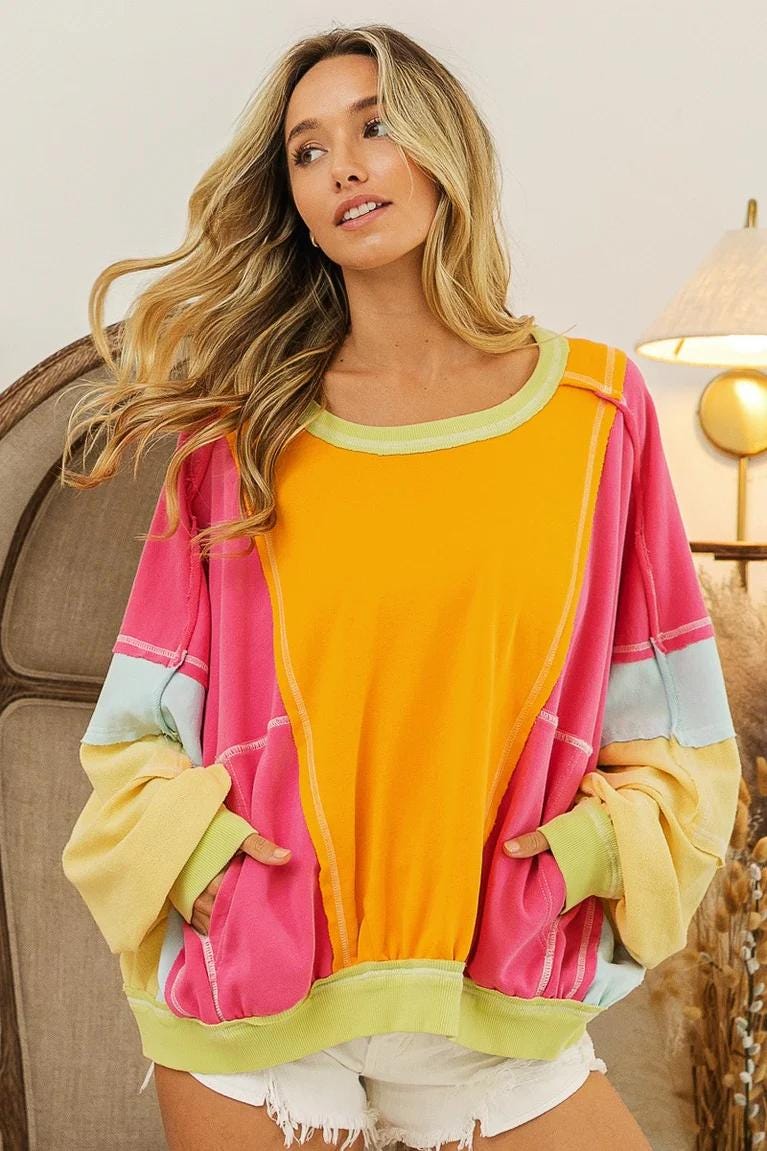 Front view of the neon patchwork cotton-blend sweatshirt featuring vibrant colorblock panels and exposed seams.