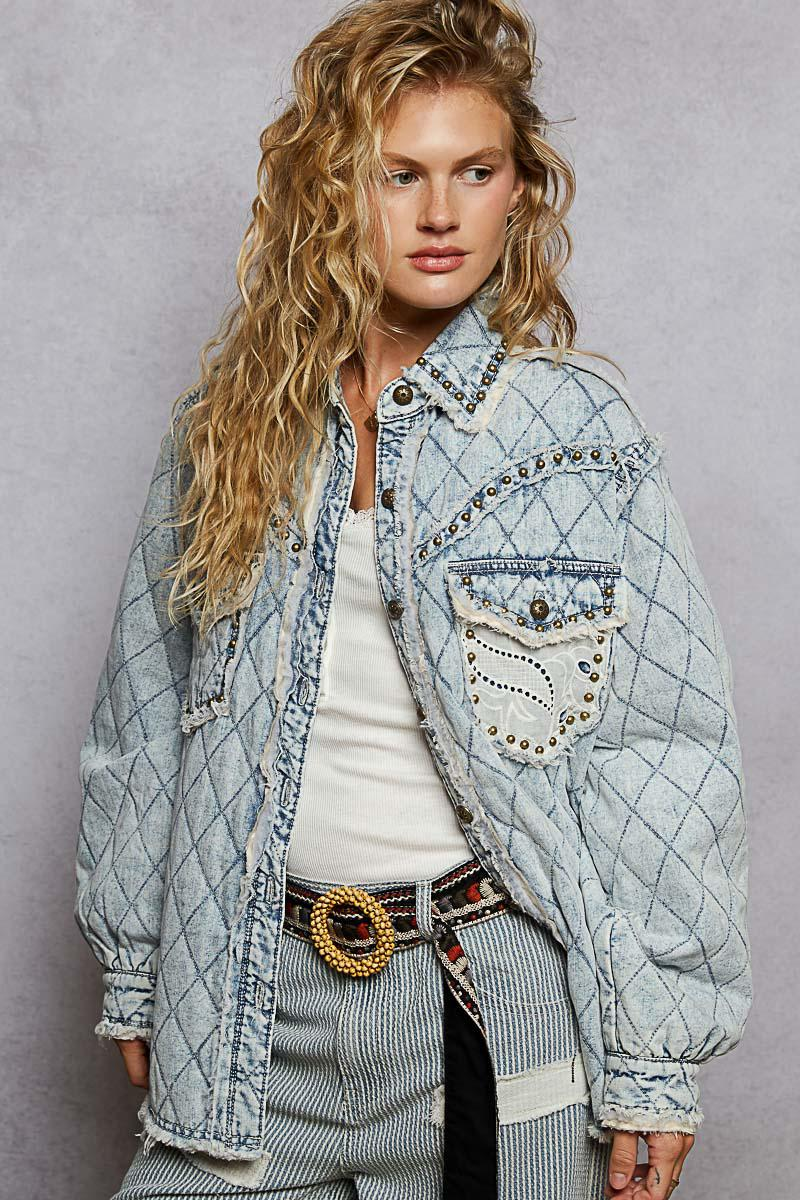 Close-up of the vintage acid wash denim texture with metallic studs and frayed edge accents