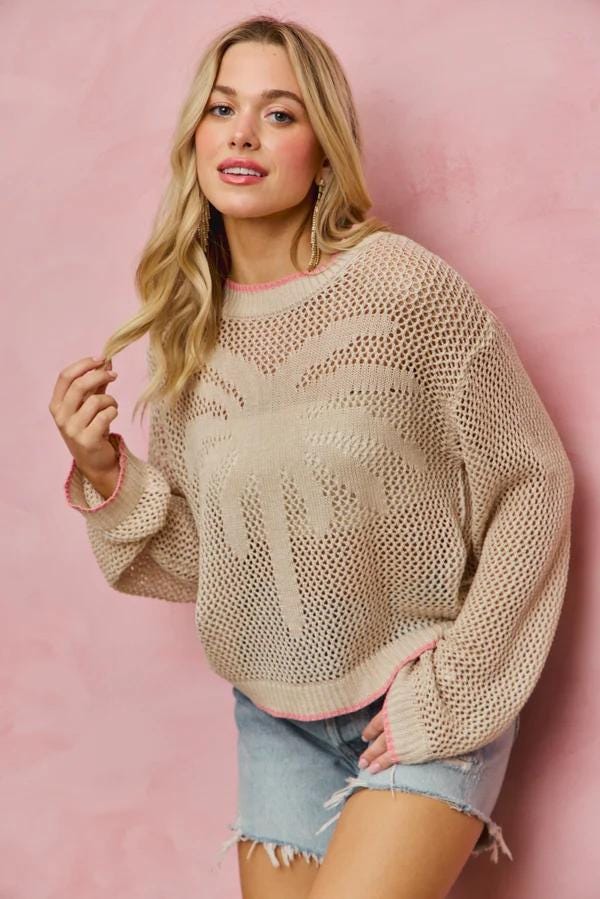 Front view of a sand-colored palm tree fishnet knit sweater with vibrant pink contrast trim for resort wear.