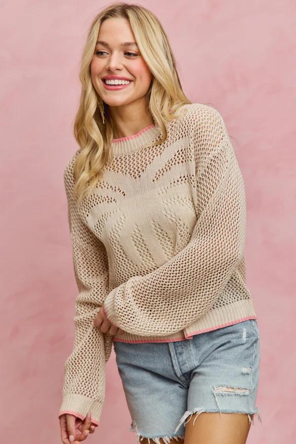 Flat lay of the cotton blend fishnet sweater highlighting the central palm tree embroidery and pink hem.