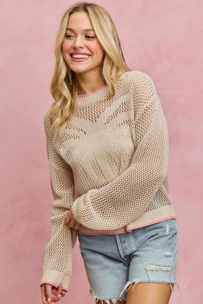 Flat lay of the cotton blend fishnet sweater highlighting the central palm tree embroidery and pink hem.
