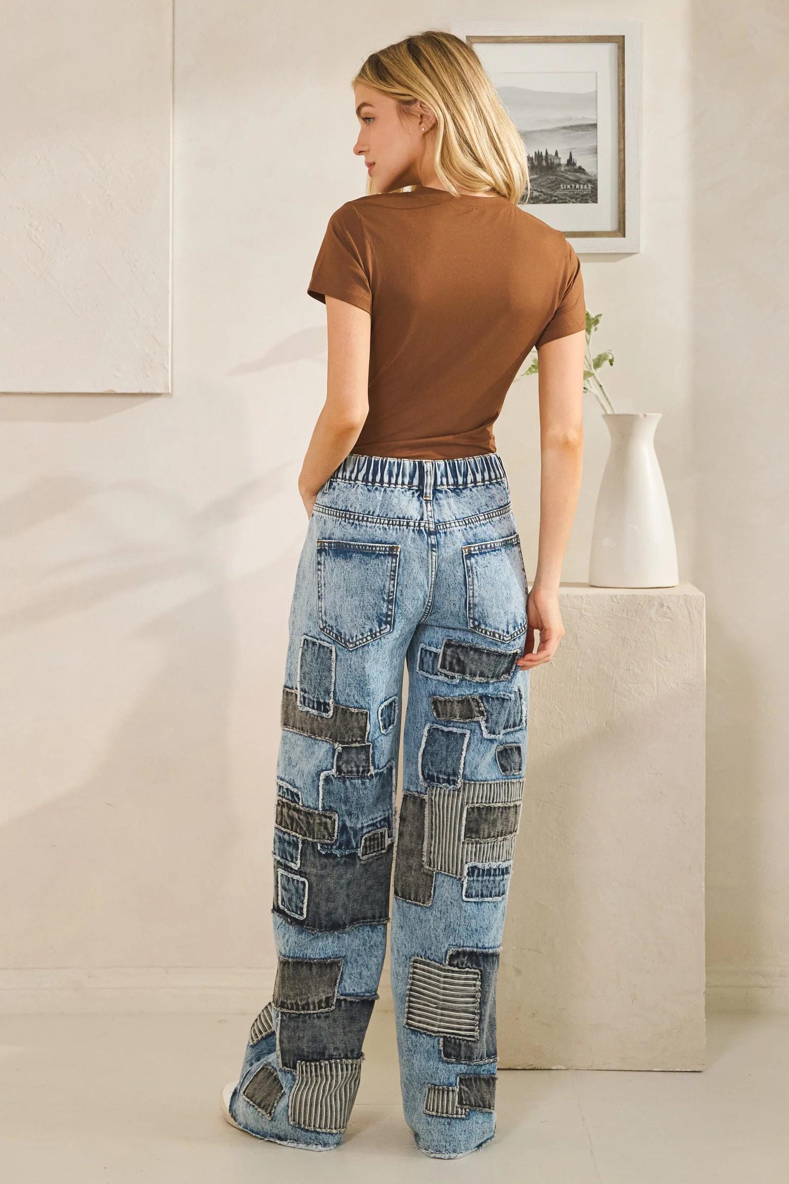 High-waisted detail of mineral wash denim jeans highlighting the button closure and belt loops