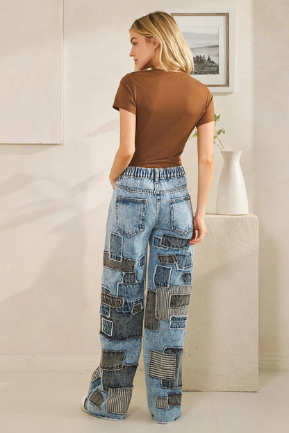 High-waisted detail of mineral wash denim jeans highlighting the button closure and belt loops