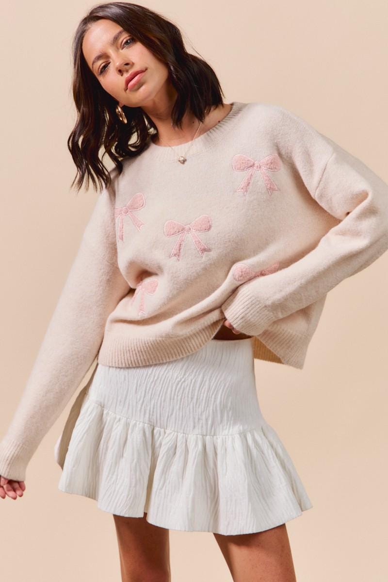 Detailed view of the ribbed cuffs and hem on the pink bow embroidered crewneck sweater