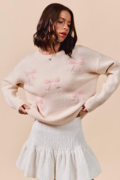Flat lay of the balletcore aesthetic knit sweater featuring scattered pink ribbon details