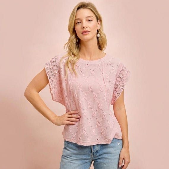 Front view of a pink eyelet top featuring delicate cap sleeves and a classic crew neckline.