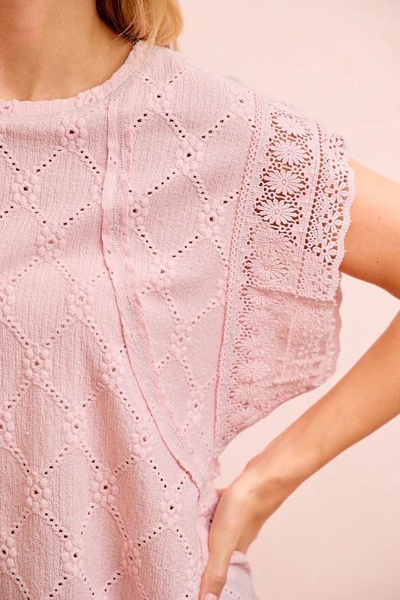 Close-up of a pink crochet knit top highlighting the contrast stitch detailing and textured gauze material.