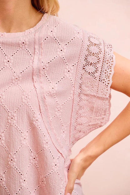Close-up of a pink crochet knit top highlighting the contrast stitch detailing and textured gauze material.