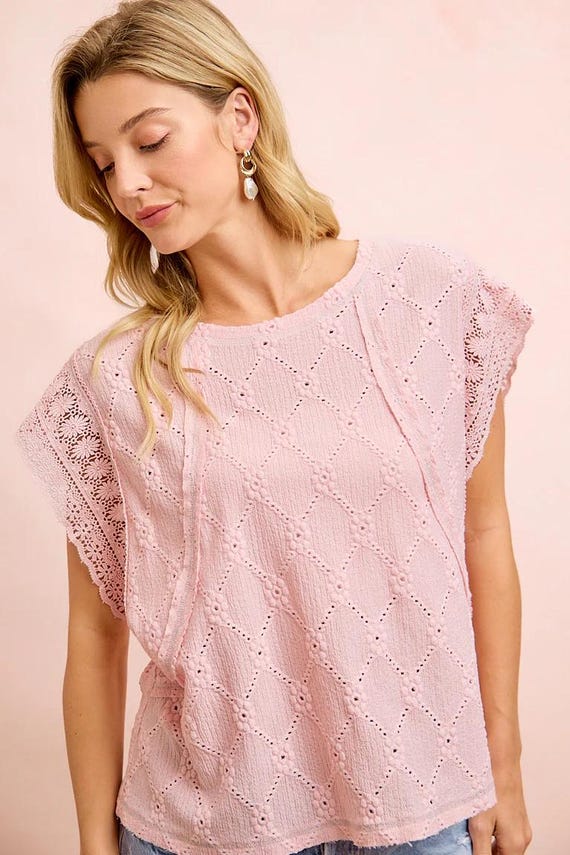 Detailed view of the flutter sleeve top with bold crochet trim and a soft pastel pink finish.