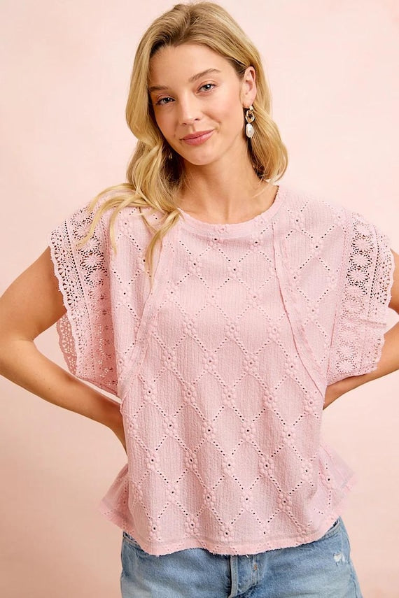 Macro shot of a floral trim blouse focusing on the delicate flower eyelet patterns and soft polyester blend.