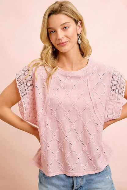 Macro shot of a floral trim blouse focusing on the delicate flower eyelet patterns and soft polyester blend.