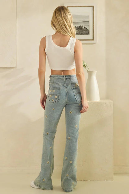 Tactile floral stitching on the hem of sun-faded denim aesthetic embroidered flare jeans