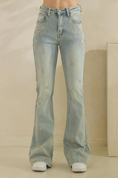 High-waisted fit of light wash blue vintage-inspired jeans with whimsical floral accents