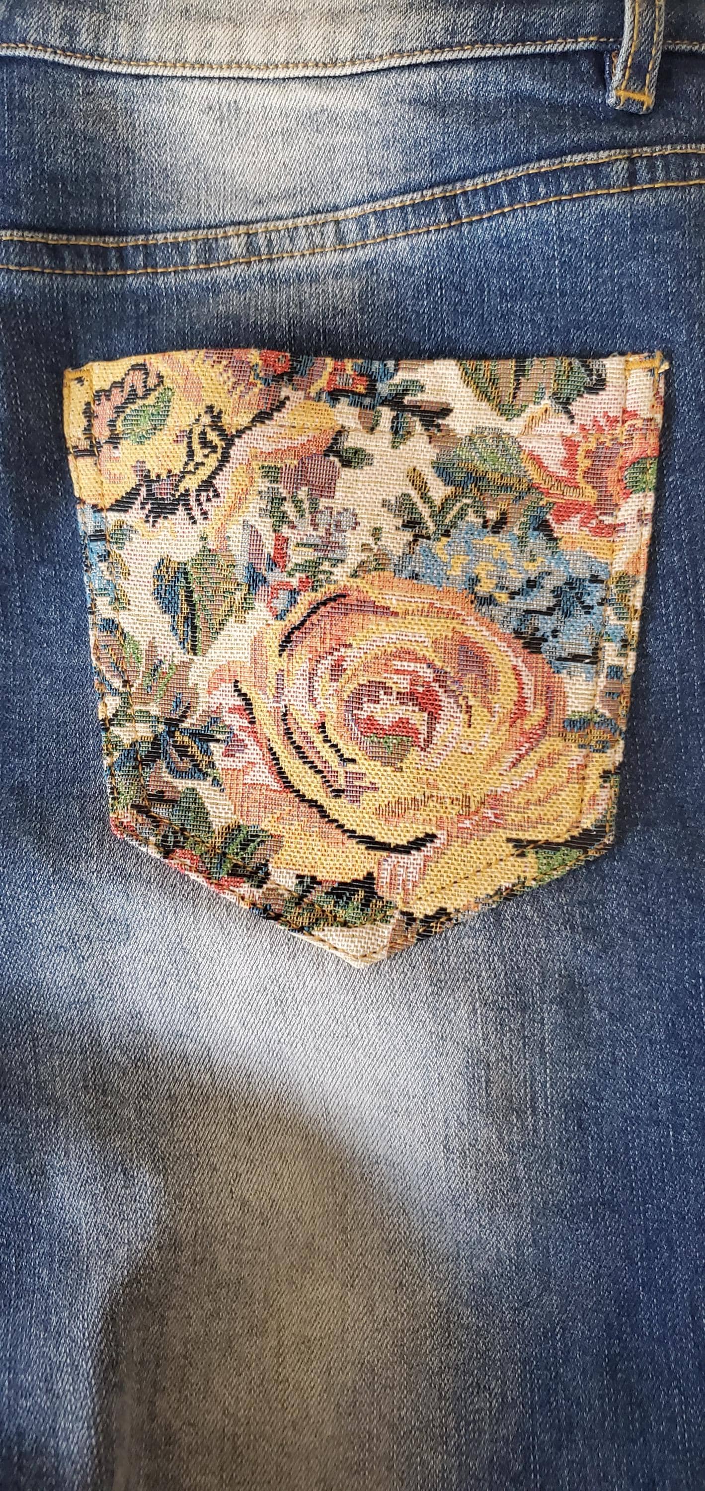Texture detail of vintage-style floral rose panels on medium wash blue flared denim.