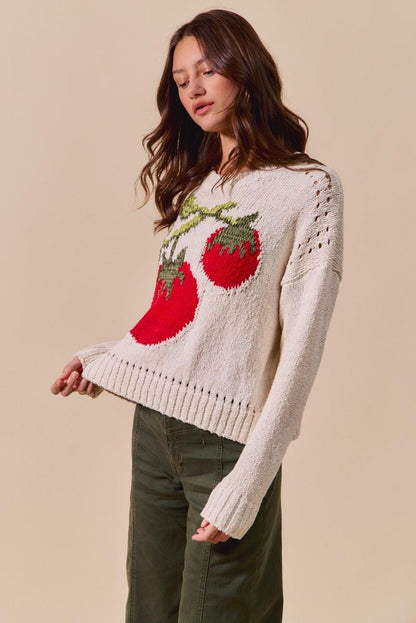 Lifestyle shot of a model wearing the gardencore tomato sweater in a lush outdoor setting