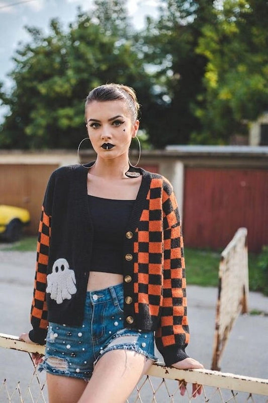 Front of oversized orange and black checkerboard ghost sweater with asymmetric split panels and V-neck