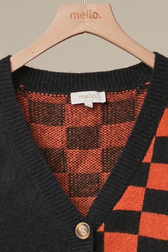 Side angle of the slouchy checkerboard knit cardigan highlighting the vibrant orange and black sleeves