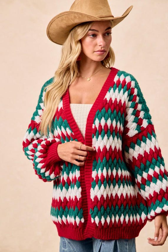 Model styling a red and green diamond knit winter sweater with high-waisted blue jeans and gold jewelry