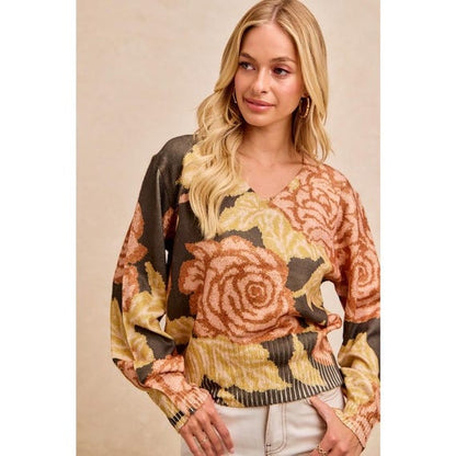 Woman in a Whimsigoth dark floral knit sweater with balloon sleeves and peach, yellow, and green rose patterns.
