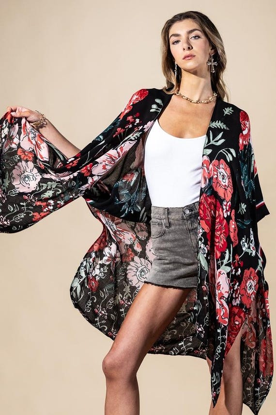 Close-up of black floral viscose kimono showing high-contrast red and pink blossoms on fluid fabric.