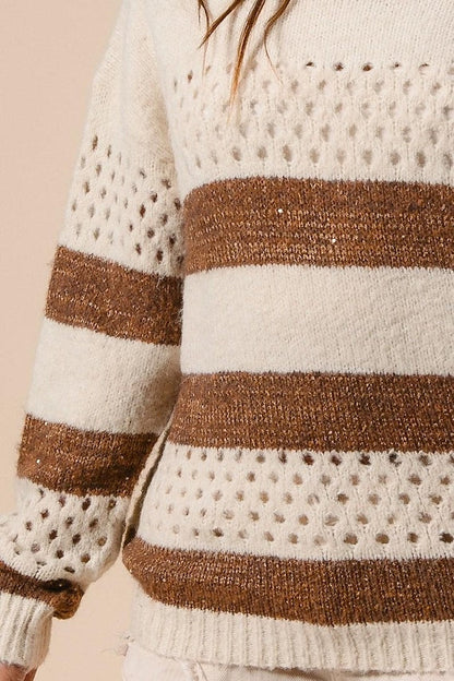 Close-up of a women's cream and brown striped knit sweater featuring a perforated open-stitch pattern.