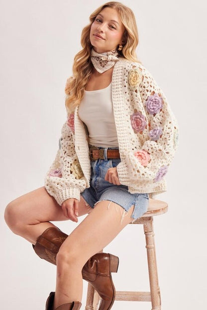 Close-up of intricate open stitch crochet knit with delicate pastel 3D floral appliqués