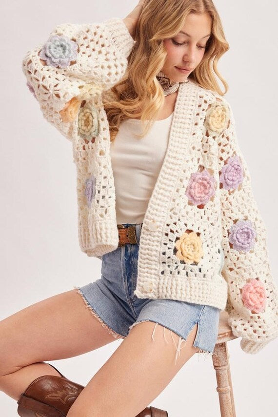 Model wearing an oversized ivory crochet cardigan with romantic balloon sleeves and floral accents