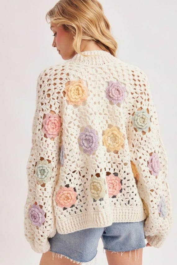 Detailed view of pastel 3D floral appliqués on the ivory open knit crochet cardigan