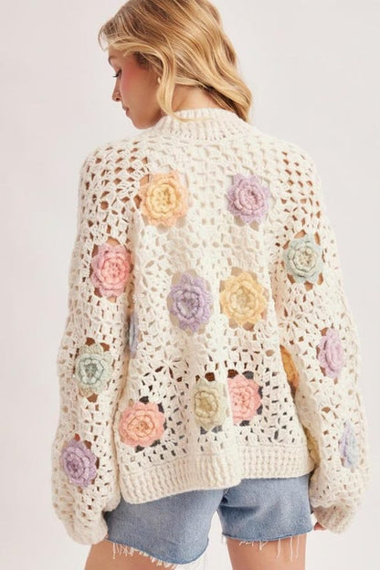 Detailed view of pastel 3D floral appliqués on the ivory open knit crochet cardigan