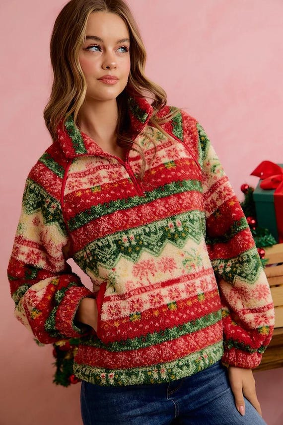 Flat lay arrangement of cozy winter fleece pullover with festive holiday mugs and winter boots.
