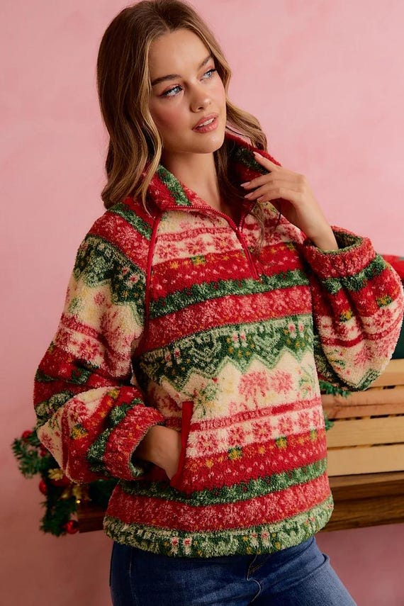 Model sitting by a fireplace wearing holiday cottagecore sweater with festive Fair Isle design.