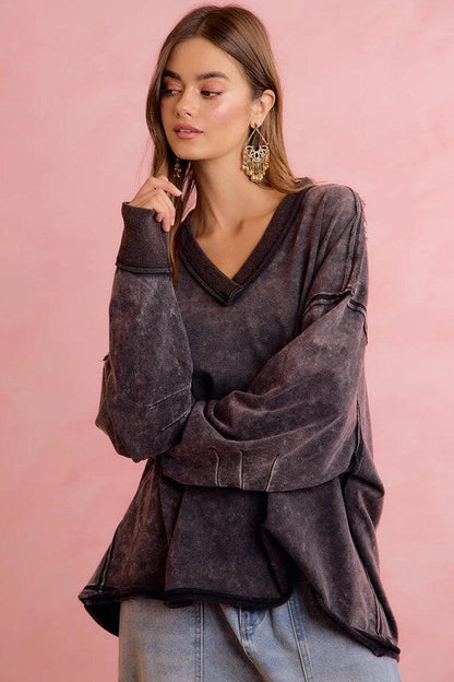 A woman wears a charcoal mineral wash oversized sweatshirt with V-neck, dropped shoulders, and raw seam details.