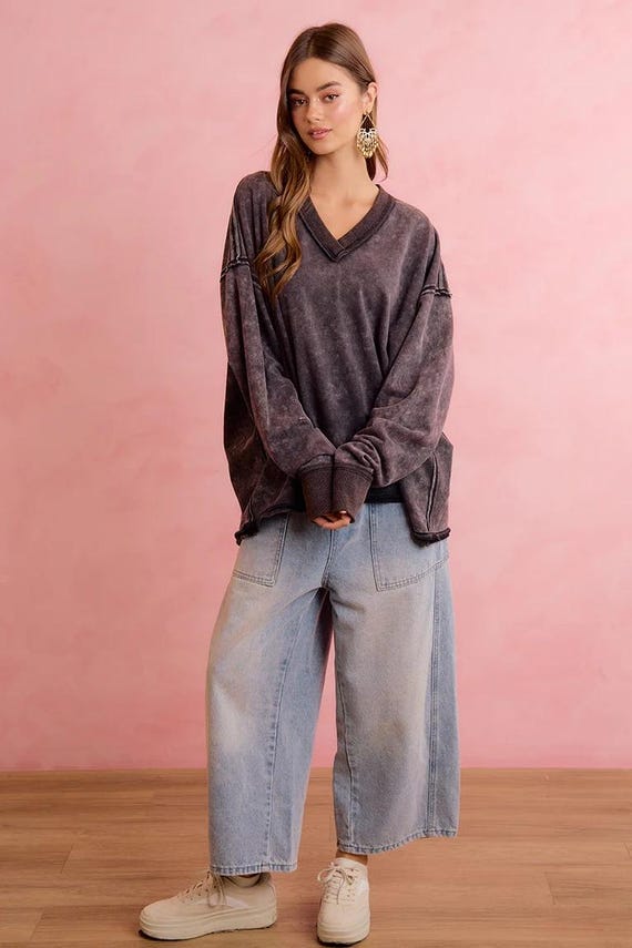 A woman wears a charcoal mineral wash oversized terry cloth sweatshirt with a V-neck and raw seam details.