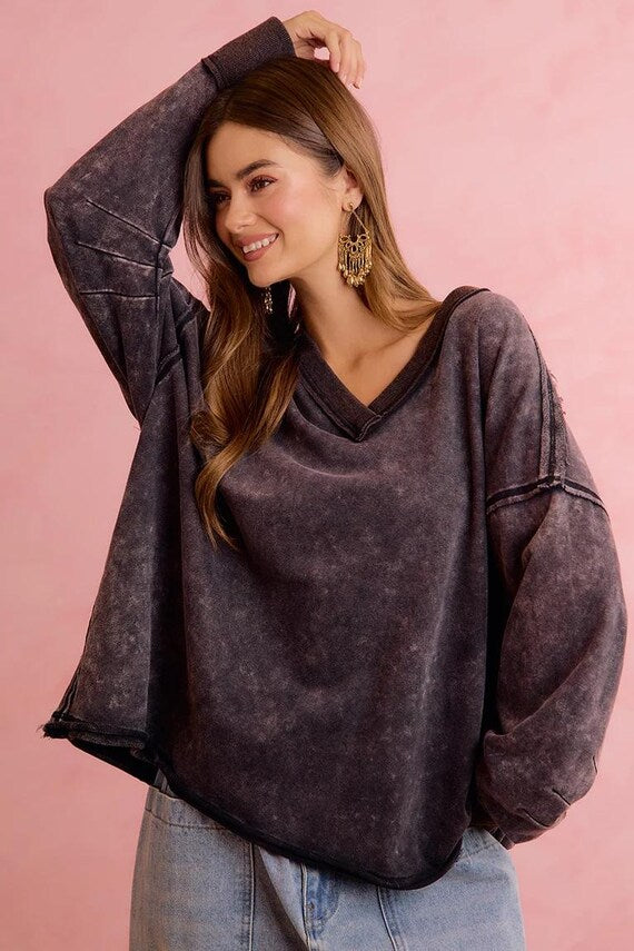 Model wears a charcoal mineral wash terry cloth sweatshirt with raw edge detailing and V-neck. Oversized fit.