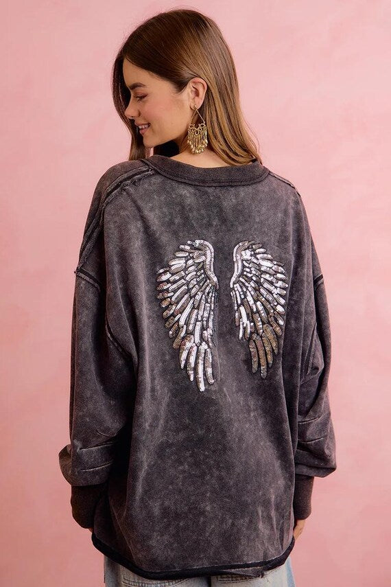 Lifestyle image of woman wearing oversized angel wing pullover for a concert outfit